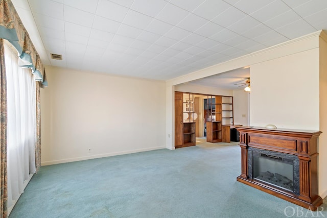 interior space featuring light colored carpet, visible vents, a glass covered fireplace, ceiling fan, and baseboards