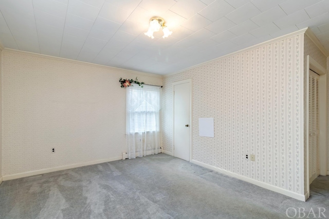 empty room with baseboards, ornamental molding, carpet, and wallpapered walls