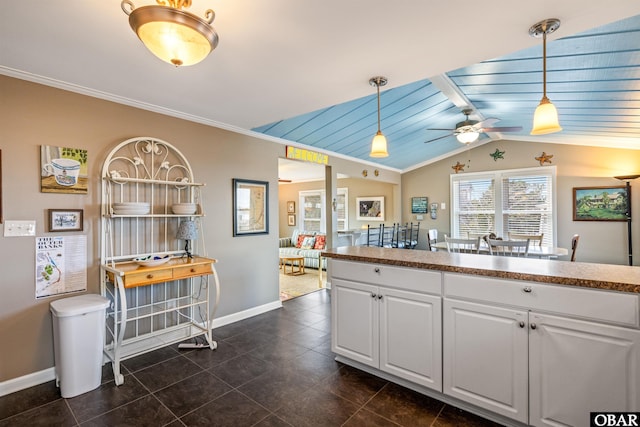 kitchen with ornamental molding, lofted ceiling, white cabinetry, and decorative light fixtures