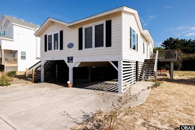 view of front of home featuring a carport, concrete driveway, and stairs