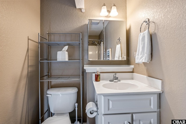 bathroom featuring curtained shower, a textured wall, vanity, and toilet