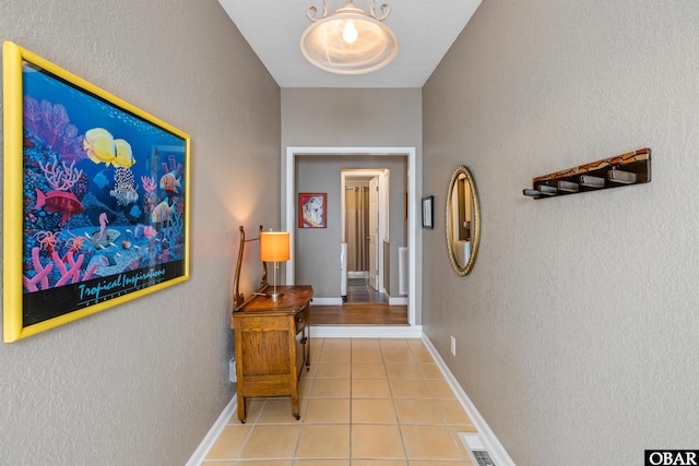 hallway featuring light tile patterned floors and baseboards