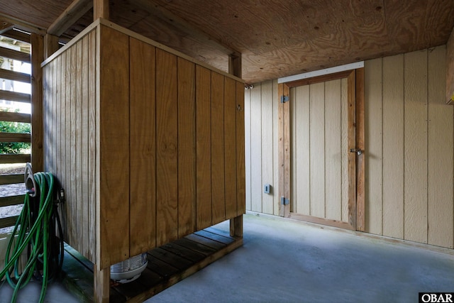 misc room featuring concrete floors and wooden walls