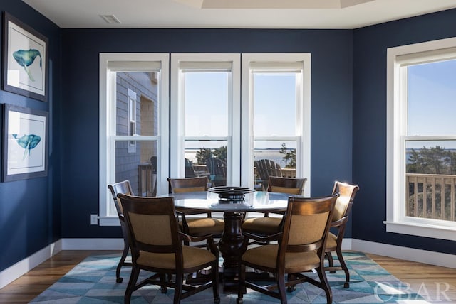 dining room featuring wood finished floors, visible vents, and baseboards