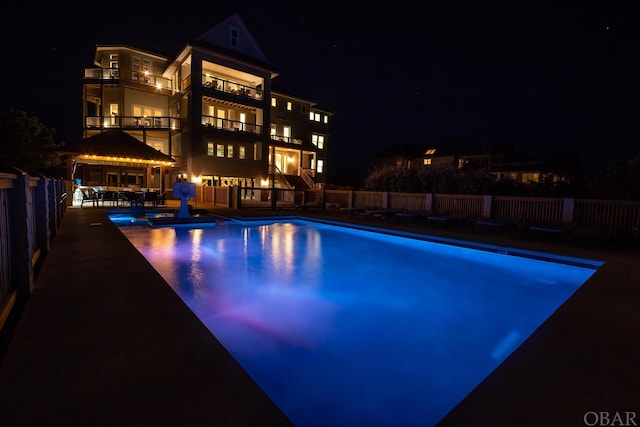 pool at twilight with a fenced in pool, fence, a gazebo, and a patio