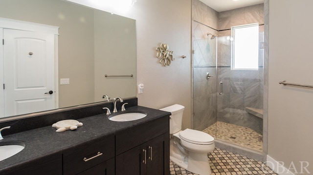 bathroom with a stall shower, a sink, toilet, and double vanity