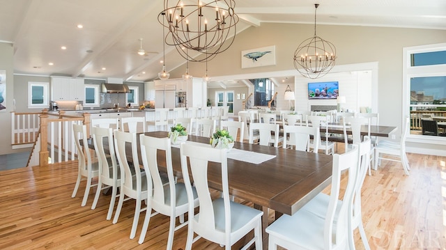 dining room with light wood-style floors, a fireplace, a notable chandelier, and beamed ceiling