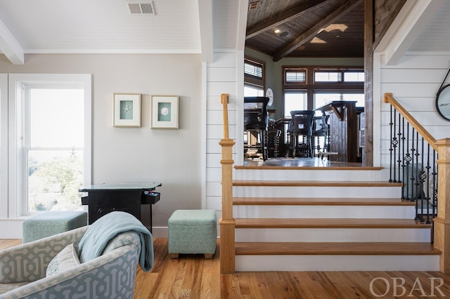 staircase with a healthy amount of sunlight, vaulted ceiling with beams, visible vents, and wood finished floors