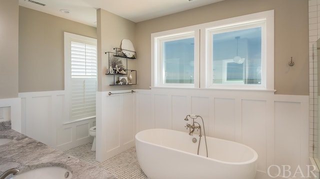 full bathroom with a soaking tub, visible vents, toilet, wainscoting, and vanity