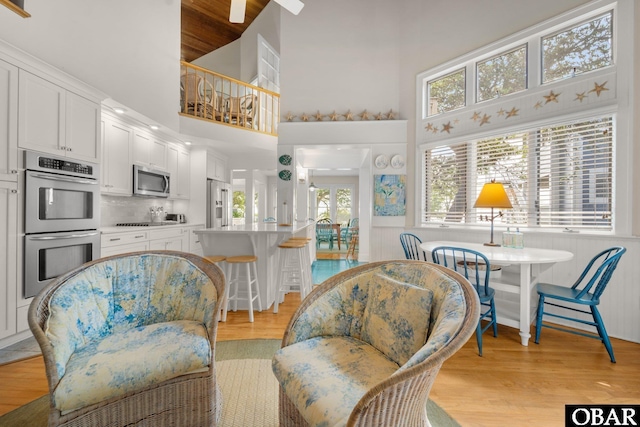1148 Dunton Dr Lot 337, Corolla, NC 27927 - living area featuring light wood-type flooring, a towering ceiling, and a wainscoted wall