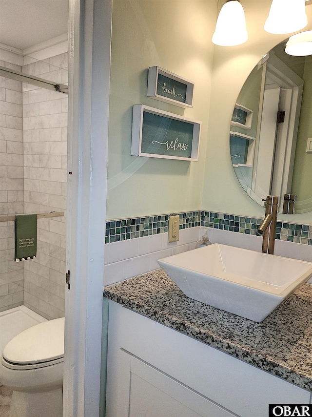 full bathroom with toilet, vanity, tile walls, a tile shower, and tasteful backsplash