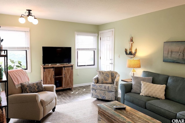 living room featuring a notable chandelier, plenty of natural light, baseboards, and wood finished floors