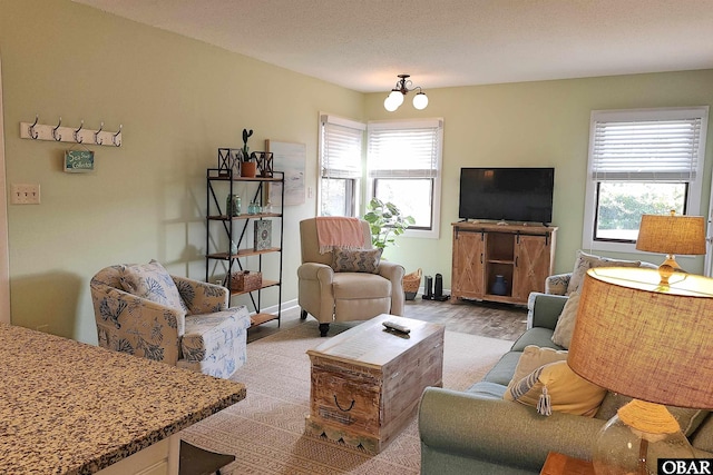 carpeted living area featuring a healthy amount of sunlight, baseboards, a chandelier, and a textured ceiling