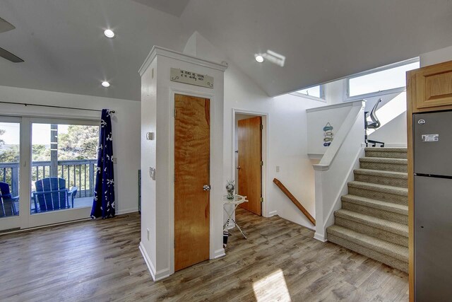 staircase with vaulted ceiling, wood finished floors, and baseboards