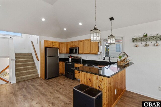 kitchen with stainless steel microwave, freestanding refrigerator, a peninsula, light wood-style floors, and range with electric stovetop