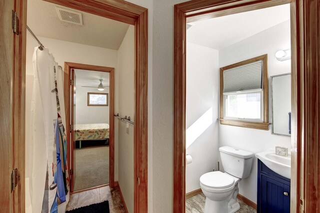 full bath with curtained shower, toilet, vanity, visible vents, and baseboards