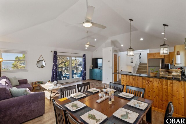 dining room with light wood-style floors, lofted ceiling, ceiling fan, and stairs