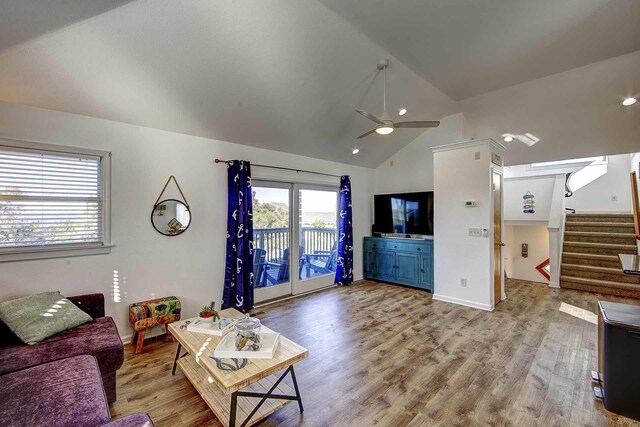 living area featuring vaulted ceiling, stairway, wood finished floors, and a ceiling fan