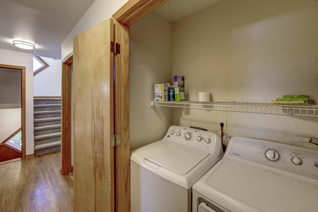 clothes washing area featuring laundry area, washing machine and dryer, and wood finished floors