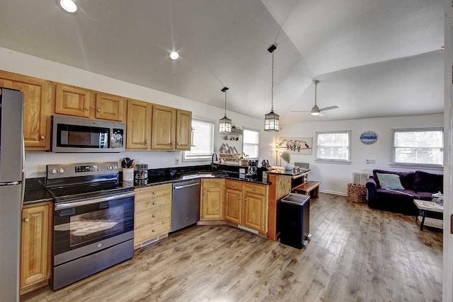 kitchen featuring lofted ceiling, dark countertops, open floor plan, stainless steel appliances, and light wood-type flooring