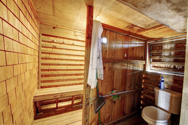 bathroom featuring toilet and wood walls