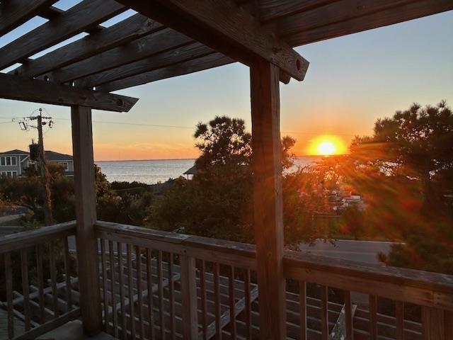 wooden terrace with a water view and a pergola