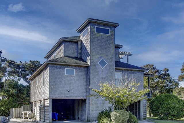 view of home's exterior featuring an attached garage and a shingled roof