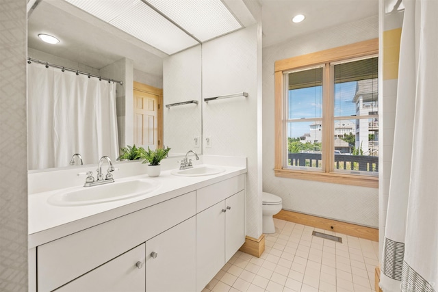 bathroom featuring toilet, double vanity, a sink, and visible vents