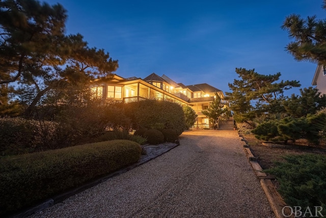 view of front of property with gravel driveway and a balcony