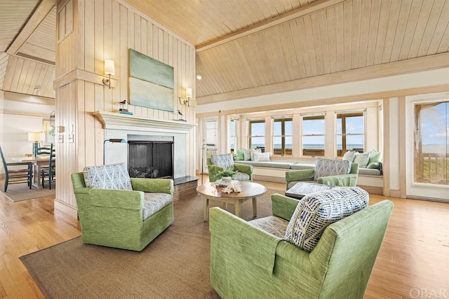 living area featuring lofted ceiling, a fireplace with raised hearth, a water view, wood finished floors, and wooden ceiling