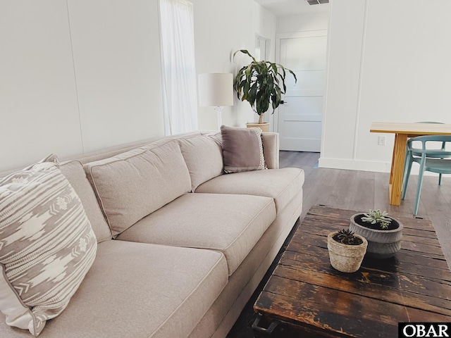 living room featuring wood finished floors, visible vents, and a decorative wall