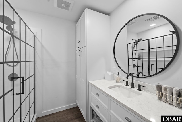 full bath featuring visible vents, vanity, baseboards, and wood finished floors