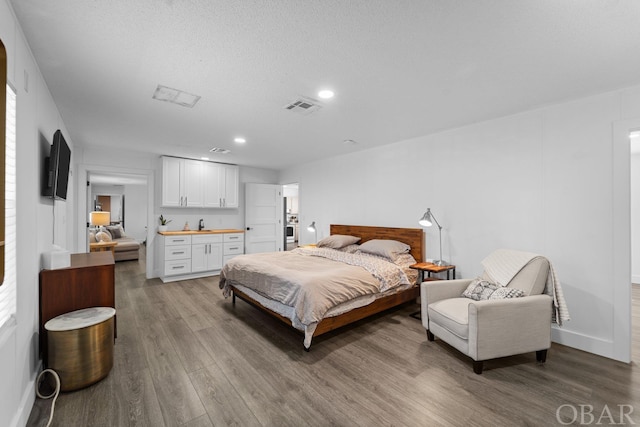 bedroom featuring light wood finished floors, baseboards, visible vents, and recessed lighting