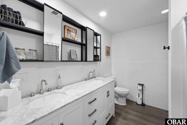 full bathroom featuring a sink, tile walls, toilet, and wood finished floors