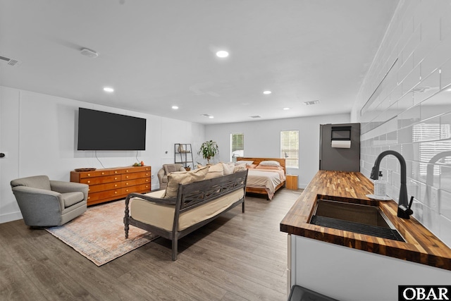 bedroom featuring light wood-style floors, recessed lighting, visible vents, and a sink