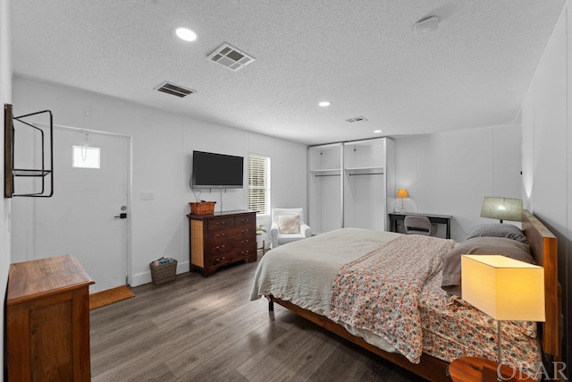 bedroom featuring a textured ceiling, visible vents, and wood finished floors