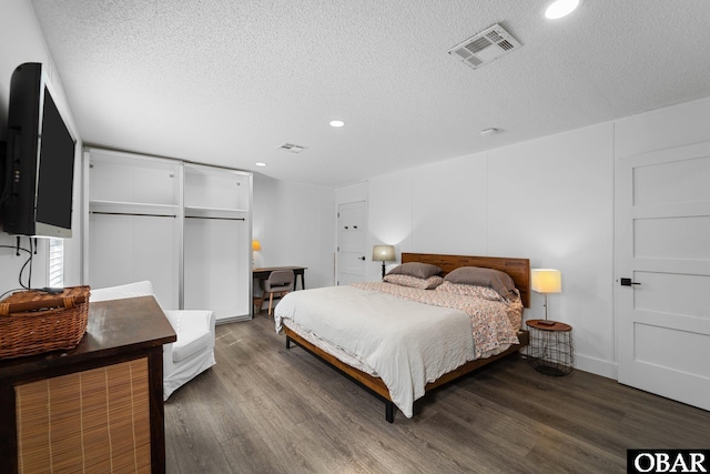 bedroom featuring dark wood-style floors, a textured ceiling, visible vents, and recessed lighting