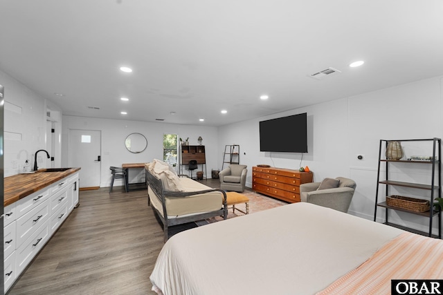 bedroom featuring recessed lighting, visible vents, a sink, and wood finished floors