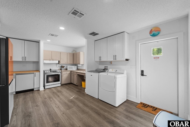 laundry area featuring washer and dryer, visible vents, and wood finished floors