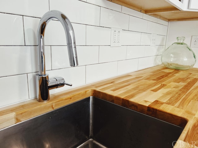 room details with butcher block counters, white cabinetry, tasteful backsplash, and a sink