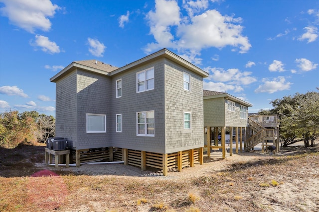 view of property exterior featuring stairs, a carport, a shingled roof, and cooling unit