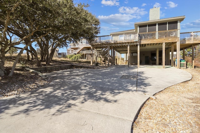 back of property with driveway, a chimney, and a wooden deck