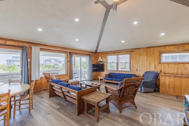 living area with lofted ceiling, light wood-type flooring, and wooden walls