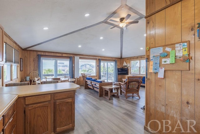 kitchen with lofted ceiling, light countertops, open floor plan, wood walls, and light wood-type flooring