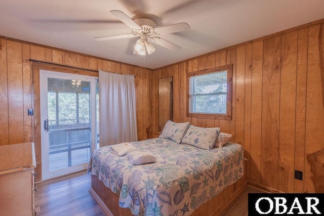 bedroom with access to outside, multiple windows, and wooden walls