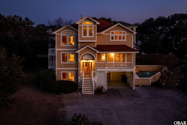 view of front facade with driveway, covered porch, stairs, and a carport