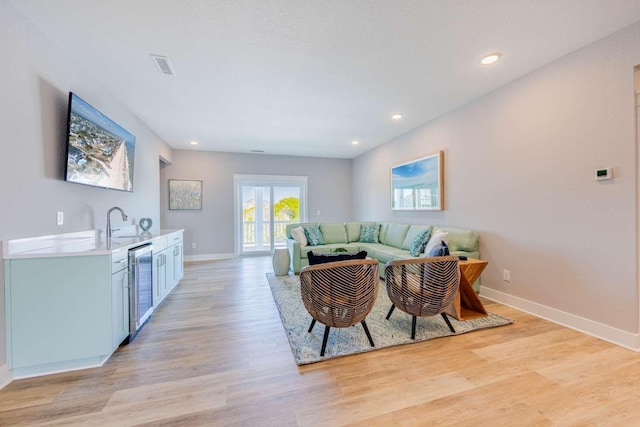 living area with light wood finished floors, beverage cooler, baseboards, visible vents, and recessed lighting