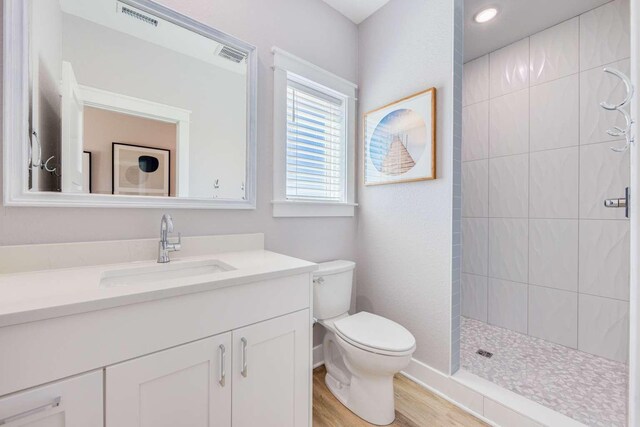 bathroom with visible vents, vanity, toilet, and a walk in shower