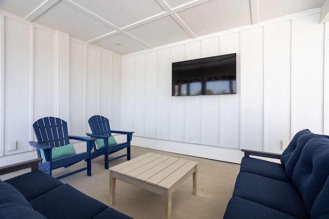 living room with coffered ceiling and a decorative wall