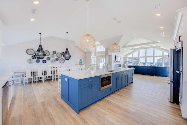 kitchen featuring a sink, open floor plan, hanging light fixtures, a large island, and a wealth of natural light